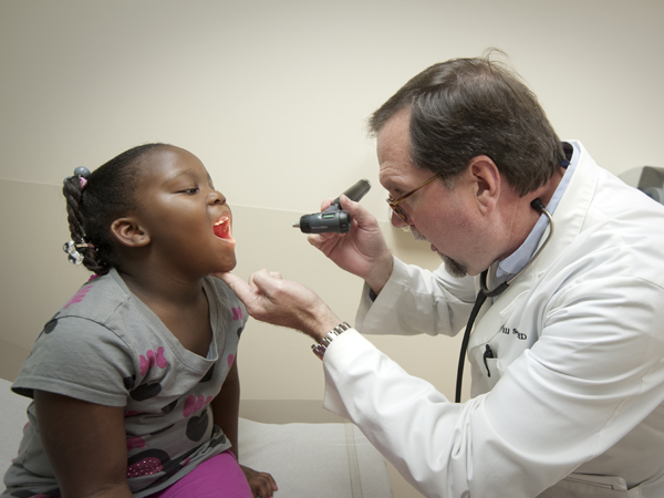 Sorey asks patient Kiara Ward of Jackson to open wide so he can look at her throat during a recent office visit