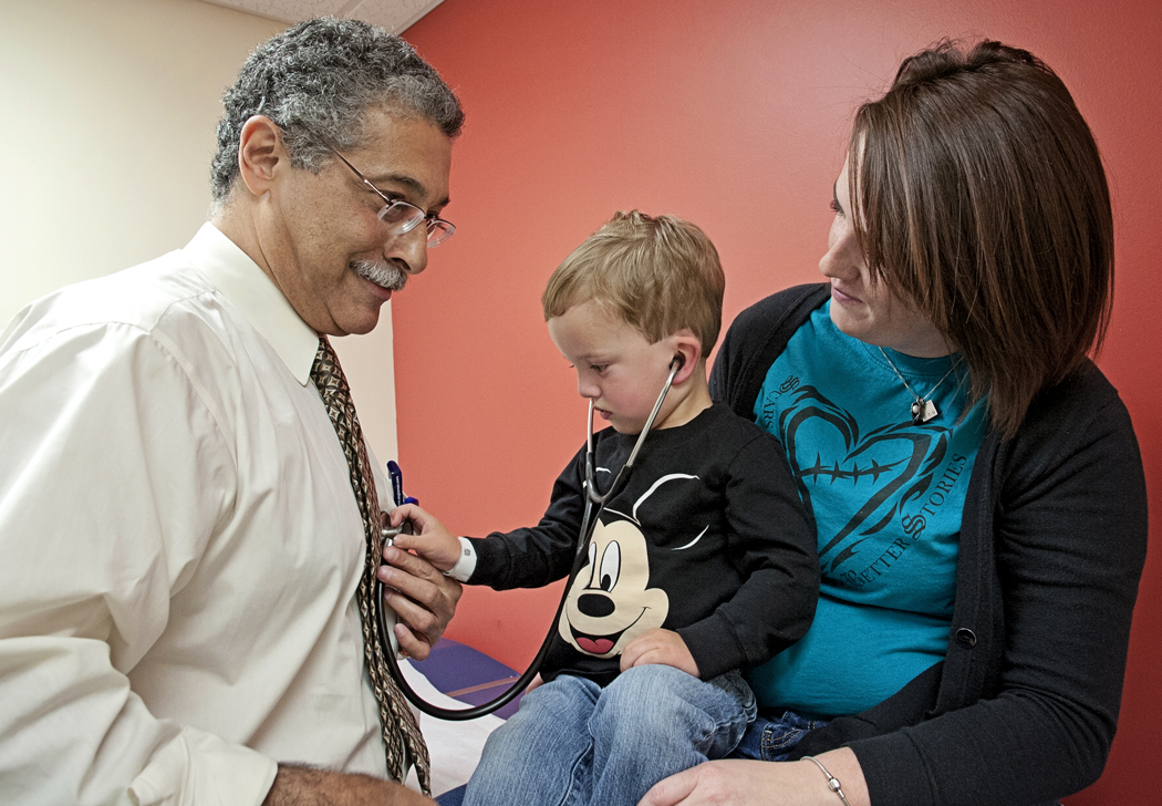 Wyatt Stout, 2, of Pass Christian listens intently to the heart of his cardiologist, Dr. Makram Ebeid, UMMC professor of pediatric cardiology and director of the Pediatric Catheterization Lab, as Wyatt and his mom, Lindsey, complete a follow-up exam.