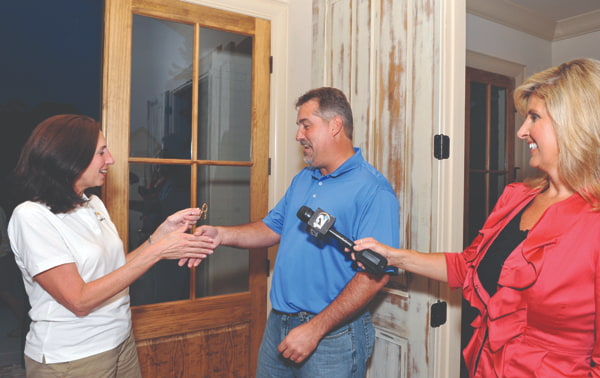 Friends board member Donna Windsor opens the door for David Butler, winner of the 2011 MiracleHome, presented by Trustmark National Bank, while Linda Allen, formerly of WJTV, waits for an interview.