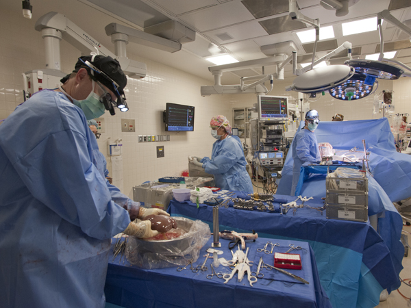 As Dr. Mark Earl (back, right) watches, Dr. Christopher Anderson gently lifts the donated liver to be transplanted into patient Dennis Mitchell. Surgery tech Alana Lowe (center) assists.