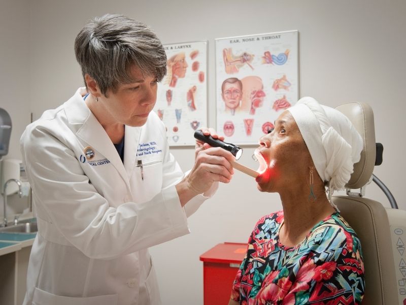 Dr. Lana Jackson, associate professor of otolaryngology and communicative science, examines the mouth of patient Bettye Lovelady during a Cancer Institute-sponsored oral cancer screening event.