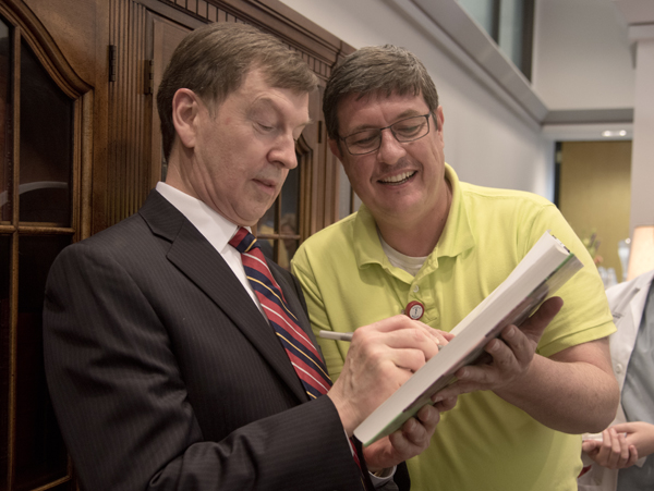 Dr. Robert Lewis, left, signs a copy of the Historical Atlas of Immunology for Dr. Stephen Stray, right, associate professor of microbiology. The book was co-authored by Lewis and Dr. Julius Cruse, both of whom were honored by a retirement reception Thursday in the Rowland Medical Library.