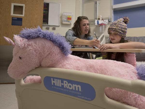 Teacher Allyn Self goes over a lesson with Allyson Hewitt of Sumrall while a pink unicorn naps in the foreground.