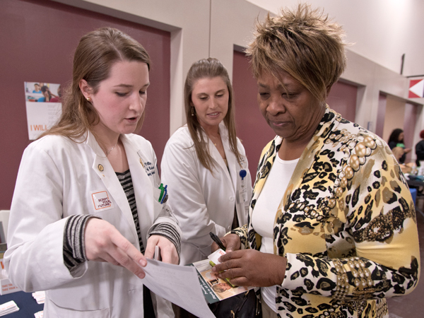 School of Pharmacy students, Courtney Phillips, left, and Kristen Chesteen, center, signed up for the Script Your Future event through the GiveGab platform. They are discussing the importance of prescription adherence to health expo attendee Treshaundra Jones.