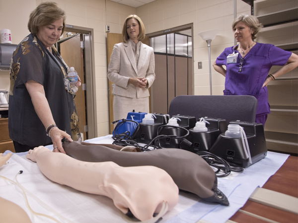 Dr. Kim Hoover, dean of the School of Nursing, center, spent the morning touring Vandergriff, left, through the school, including a stop in the simulation lab where MacSorely, right, demonstrated advances in simulation equipment such as the artificial arms students use to practice starting I.V. fluids.