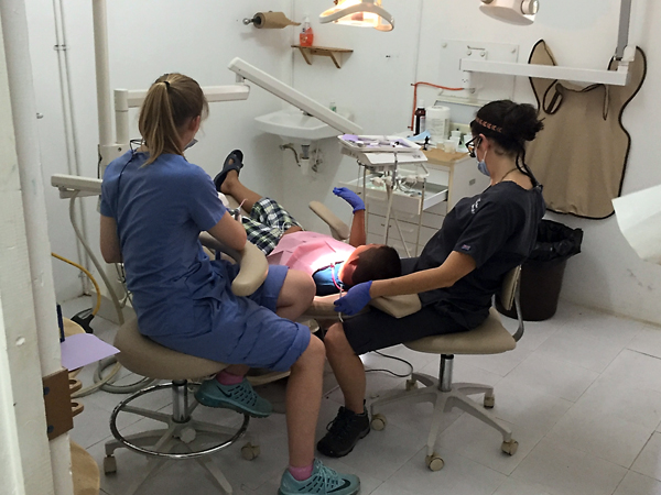 Dental students Chauncey Craft, left, and Chelsea Barr provide treatment to a pediatric patient at the mission dental clinic in Belize.