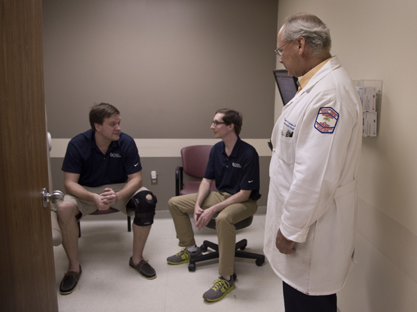 Orthopaedic surgeon Dr. William Geissler, right, waits for patients in the Friday night football clinic with second-year orthopedic residents Dr. Miles Hulick, left, and Dr. Paul Williams.