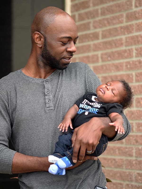 Joey Robinson holds his son, Joelsteen, outside the UMMC Cancer Institute.