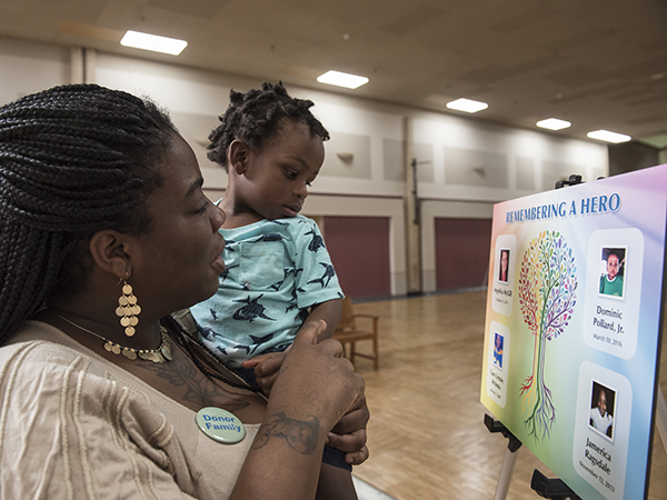 Bennett son Dmarley Pollard as she stands next to a poster bearing the photograph of her late son and Dmarley's twin, Dominic Pollard Jr.