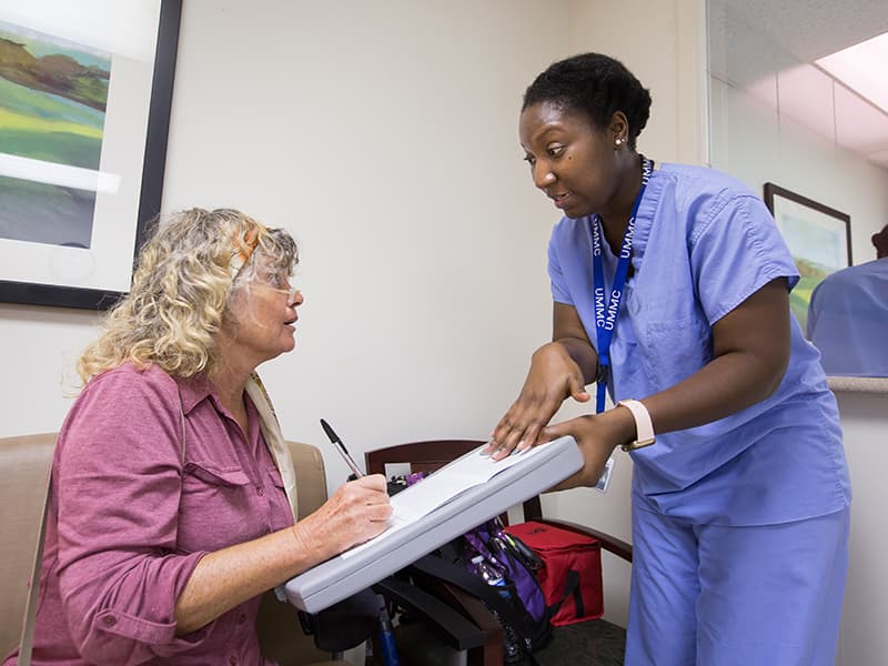 Angela Brooks, seated, gets assistance in signing up to be a participant of the UMMC Biobank's 10k program from Tyesha Younger, a biorepository specialist.