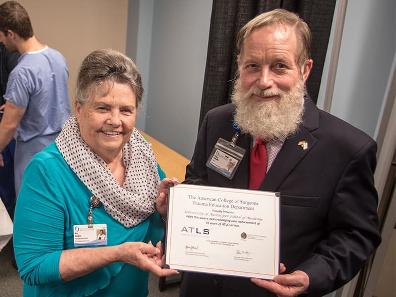 Kay Watkins, program administrator of the Division of Continuing Health Professional Education; and Dr. Greg Timberlake, an ATLS instructor and professor emeritus, hold the certificate recognizing UMMC's trauma life support training program for 30 years of operation.
