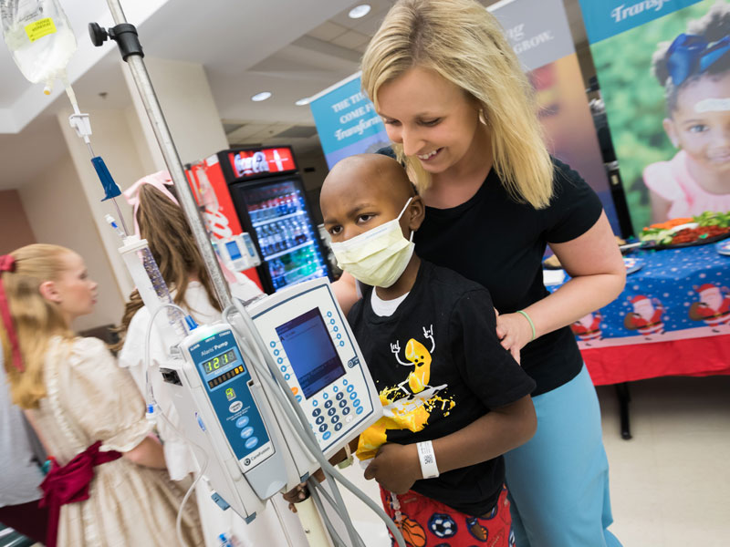 Child life specialist Tiffany Key and patient Rico Jones Jr. of Canton enjoy the reception following BankPlus Presents Light A Light. The event was moved to the Wiser Hospital for Women and Infants cafeteria due to the start of construction for a new children's tower adjacent to Batson Children's Hospital.
