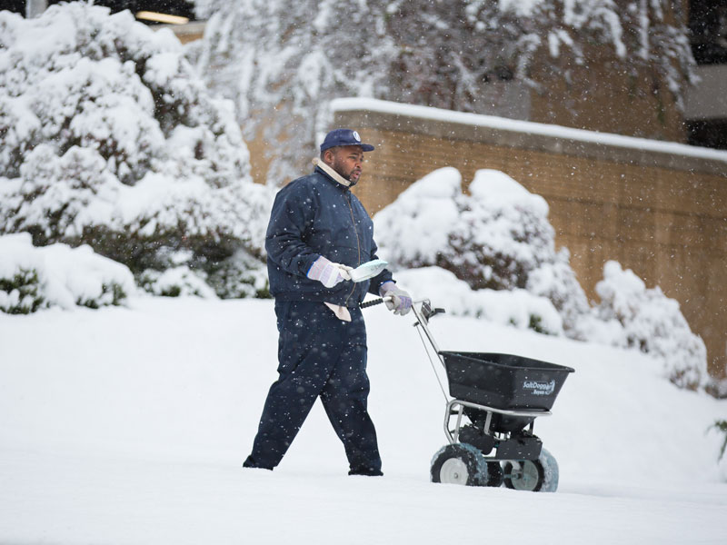 Kinard Anthony, groundskeeper, spreads deicer on the sidewalks in front of the hospital.