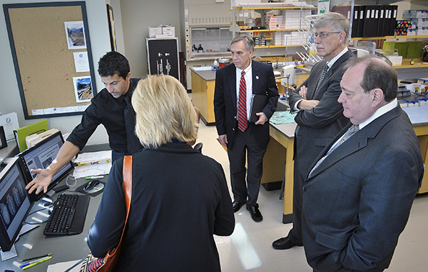 Professor of physiology and biophysics Dr. Alejandro Chade, back left, describes his research to professor and chair of physiology Dr. John Hall, center, and NIH director Dr. Francis Collins, back right, during Collins’ 2012 visit to UMMC.
