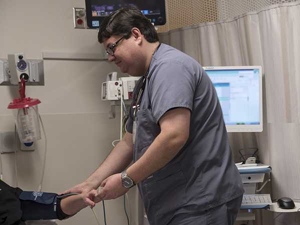 Nurse John Lentz visits with a patient while her vital signs are being fed into the new medical records system.