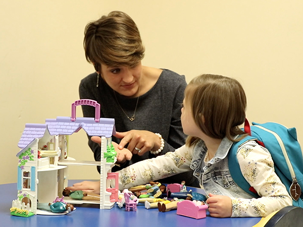 Sarah Nasif asks daughter Mia to share a doll during a therapy session.