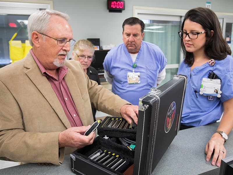 David Bowman, left, a former cancer patient, shows his harmonicas to CICU staff members, from left, Cynthia Gonzalez, housekeeper, Don Horn, nurse manager, and Presly Lowry, R.N.