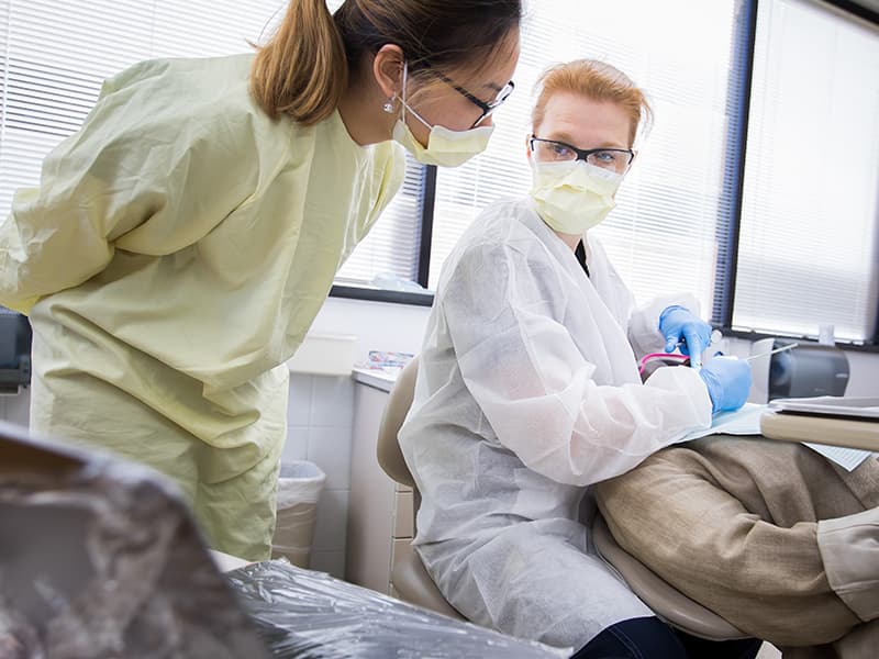 Jennifer Bain, center, associate professor of dentistry, and Jolie Nguyen, left, third-year dental student, perform a periodontal exam for Sara Williams.