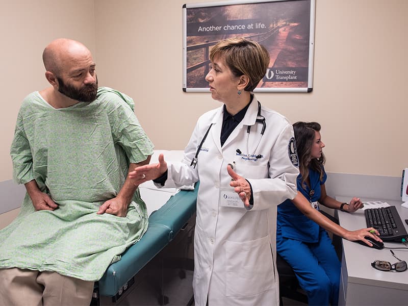 Dr. Iasmina Craici, associate professor of nephrology, talks to Tim Murphree of Tippo about his blood sugar levels during a follow-up appointment after his pancreas-kidney transplant. Recording the information is his abdominal transplant coordinator, Kristen Turnbow.