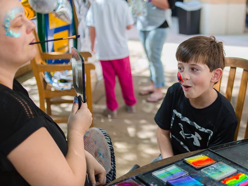Evan Reynolds is shown his face paint by artist Emily Schmidt during a party at Batson hosted by the Mississippi Children's Museum. Ryan's sister, Emma, is a patient at Batson.