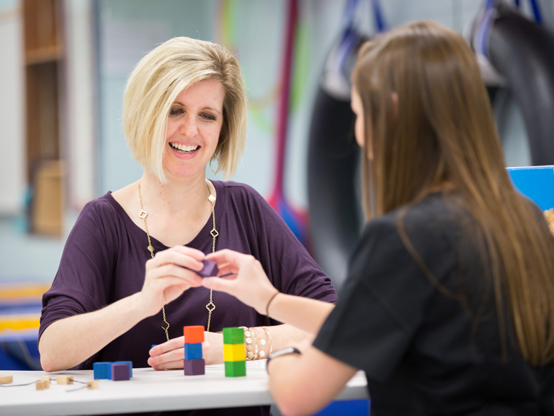 Ladner, left facing camera, teaches Herrington the use of small blocks in the development of fine motor skills for pediatric patients.