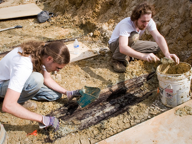 In this file photo from March 2013, Derek Anderson, left, and Forrest Follet from the Cobb Institute of Archaeology, Mississippi State University, remove the soil from the lid of one over 35 graves uncovered during construction.