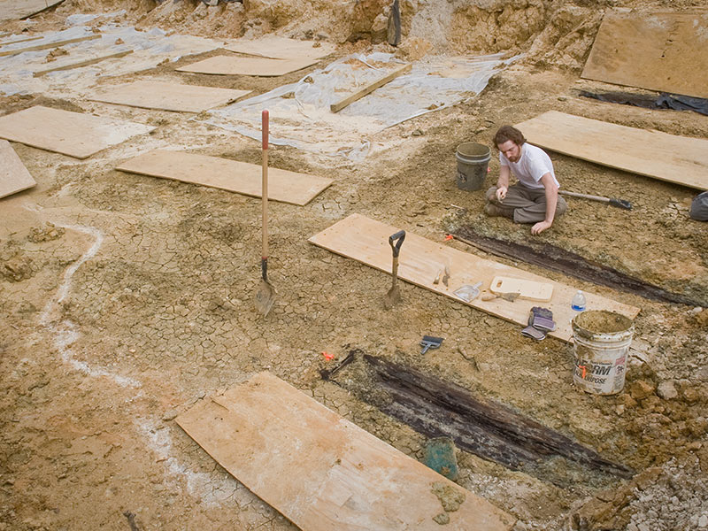 In this file photo from March 2013, Follet removes the soil from the lid of one over 35 graves uncovered during construction.