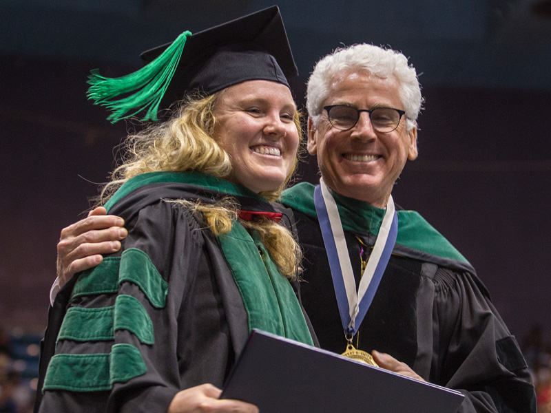 New School of Medicine graduate Claire Harkey celebrates with her father, Dr. Louis Harkey, immediately after he hooded her during May 25 commencement exercises.
