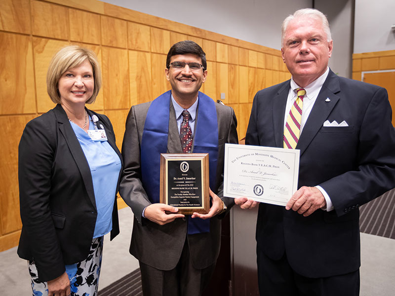 Dr. Amol Janorkar, center, accepts a plaque and certificate pronouncing him recipient of the 2018 Regions TEACH Prize from Dr. LouAnn Woodward, left, vice chancellor for health affairs and dean of the School of Medicine, and Alon Bee, city president-metro Jackson Regions Bank.