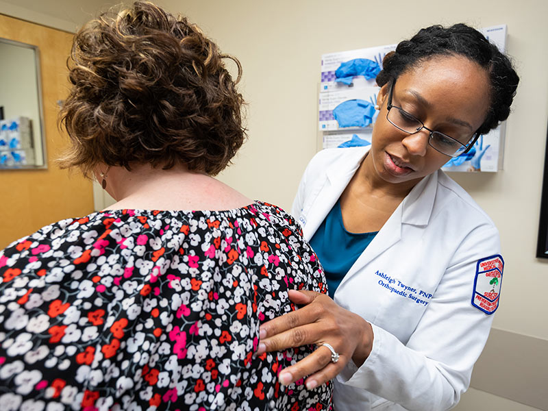 Ashleigh Twyner, nurse practitioner, checks how Amy Kittrell's compression spine fracture is healing.