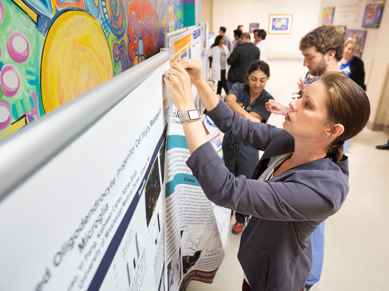 Research Specialist Lacy Malloch helps hang research posters in the hallway leading to Batson Children's Hospital.