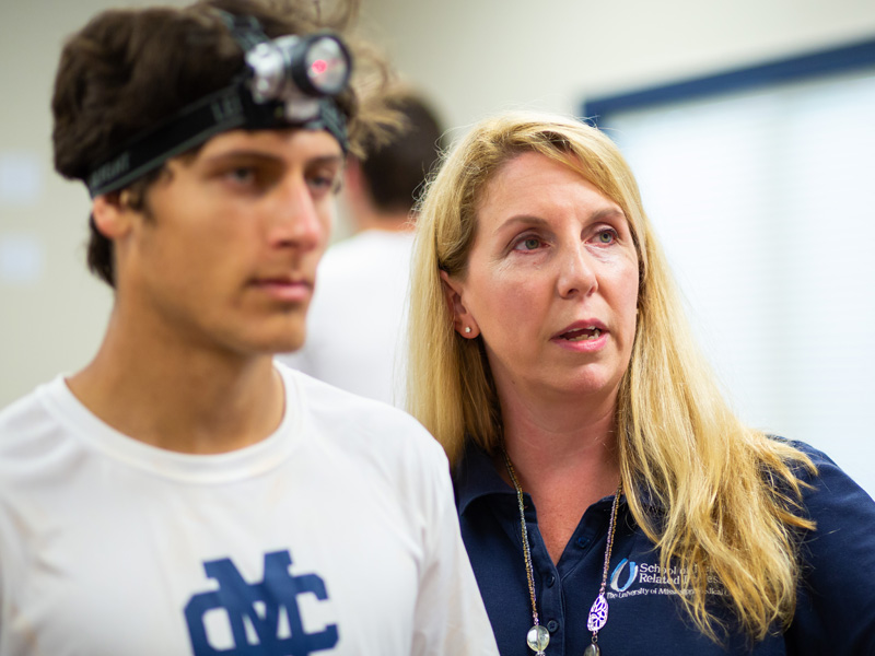 Dr. Kimberly Willis, associate professor of physical therapy, explains to soccer player Bruno Cantoni how to use a laser to follow a maze pattern.