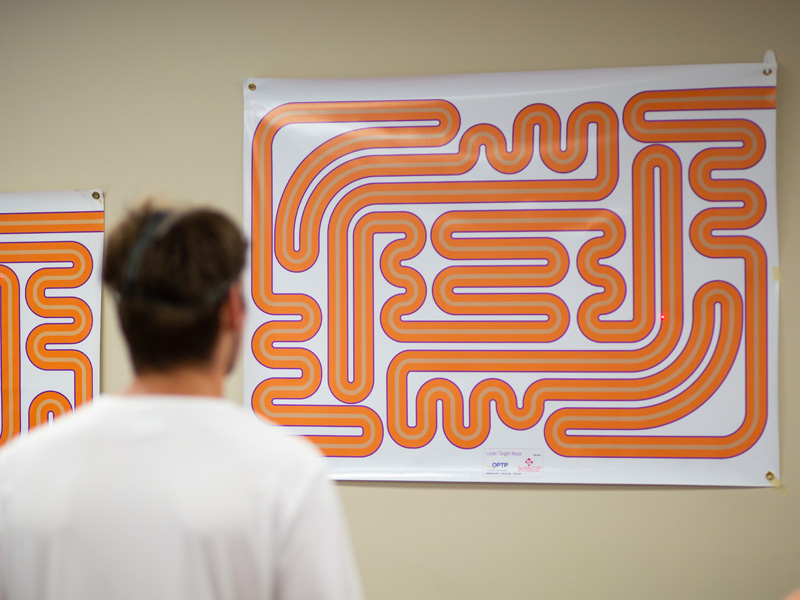 A Mississippi College soccer player uses a head-mounted laser to trace the path of a maze in an exercise designed to gauge eye control.