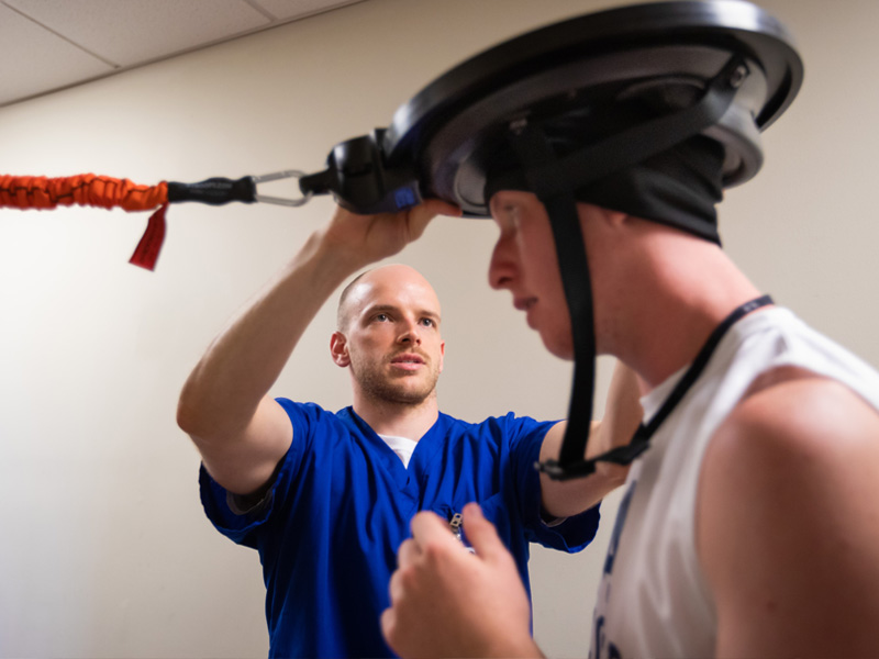 Tyler Luchtefeld, a physical therapy resident, affixes a device to soccer player Cameron Allcorn's head to test reflexes and motor skills.