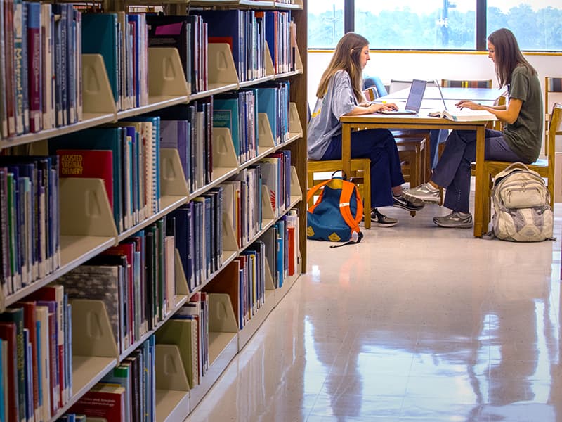 Among a sea of textbooks, Sara Spencer Pace, left, and Annie Penster, first-year School of Nursing students, prefer to access Rowland’s vast medical library content electronically.