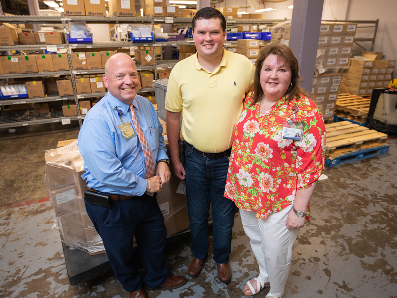Austin Tidwell, center, visits with his mother, Christy Tidwell, clinic operations supervisor at Grants Ferry, and Kenneth McCreary, interim director of supply chain logistics.