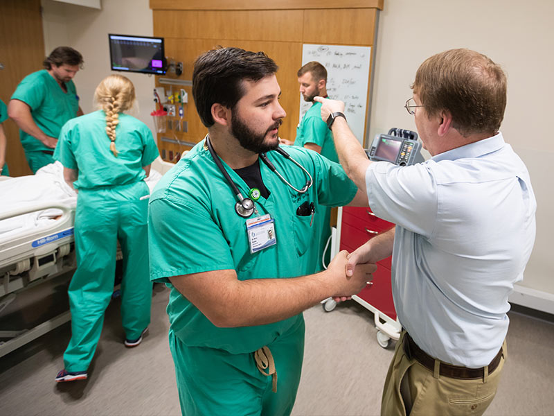 Dr. Dustin "Dusty" Bratton, left, calms down a patient's relative -- portrayed here by Orledge.