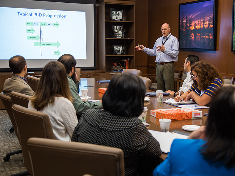 Dr. Michael Ryan, standing, gives an overview of the SGSHS's expectations for admitted students to faculty visiting from regional colleges.