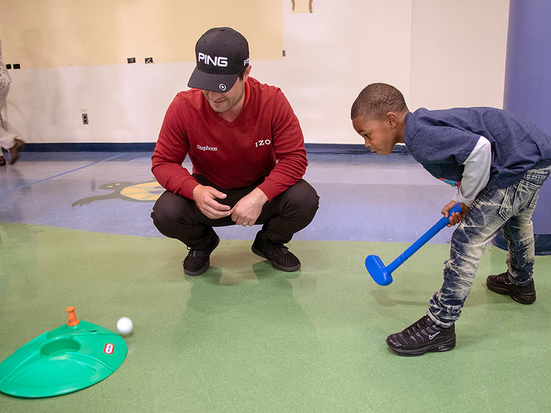 Professional golfer David Lingmirth watches as Shanerick Bounds of Forest putts.