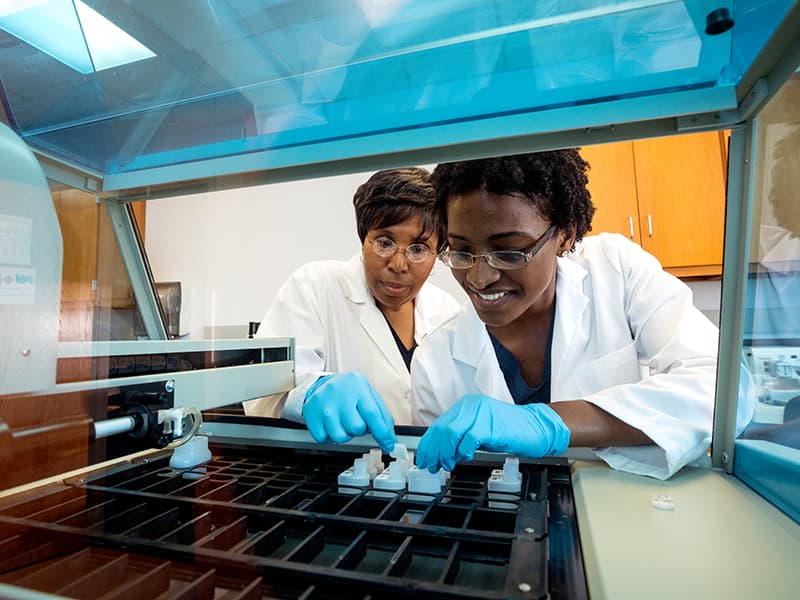 Bevilyn Perkins. left, instructor in medical laboratory science and educational coordinator of the Histotechnology Program, shows how some of the new state-of-the-art lab equipment works to Aiesha Norwood, histotechnology student.