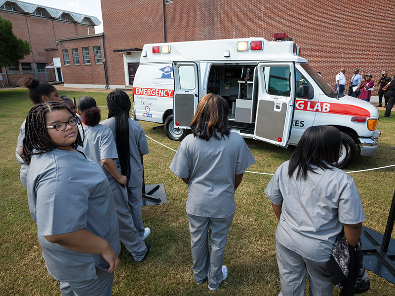 Students in Lanier High's Health Services Academy line up to get a first look at a retired ambulance donated to their program by American Medical Response.