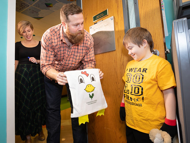 Erin and Ben Napier present a tournament gift to Children's Cancer Center patient Victor "VJ" Worrell of Vicksburg.