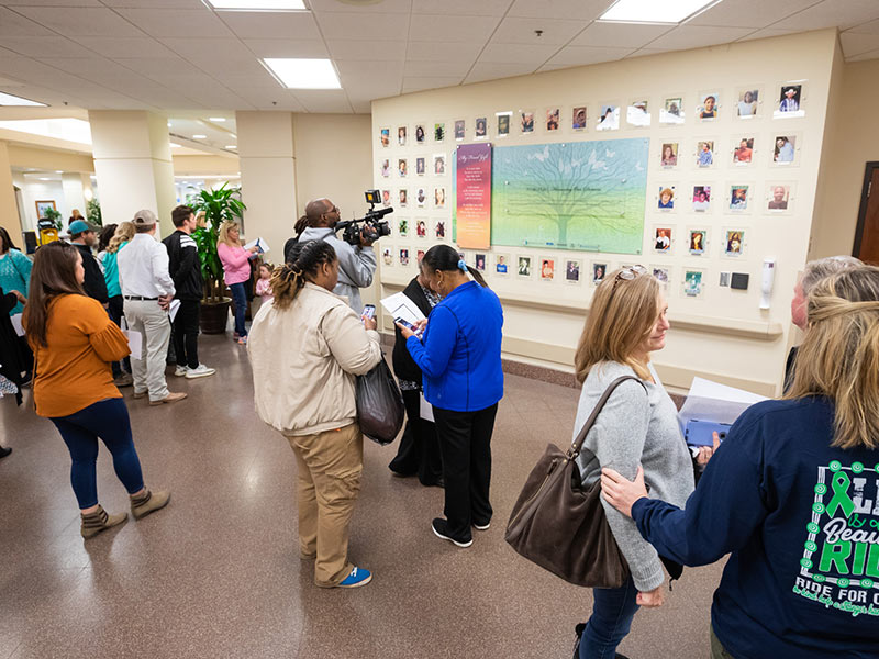 Friends and family members of those who have given the gift of organ donation look at their loved ones' photographs on the Wall of Heroes.