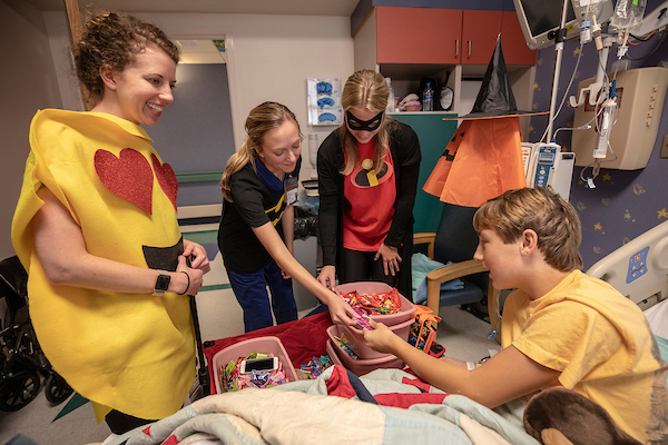 From left, pharmacy resident Lauren Pohren and pharmacy students Mallory Pullman and Anna Wright went "reverse trick-or-treating" at Batson Wednesday, dressing up and calling on patients, including Chaney Hale of Canton, to hand out treats.