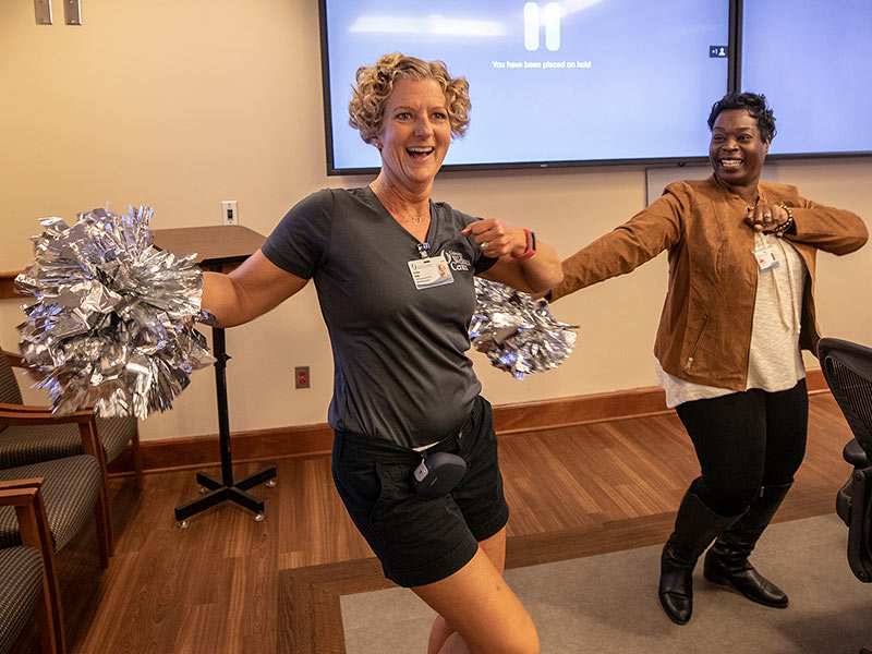 Heather Biddle, left, University Wellness coordinator for group exercise and safety, and Josilind Martin-White, Office of Patient Experience customer service representative, stretch their muscles to music during a recent 