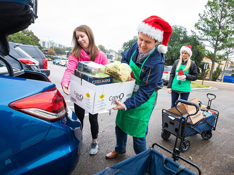 Nikki Baker, left, Clinton High School chemistry teacher and cheerleading sponsor, gives a load of toys to Ryan Mains and Emma Mikhalek, Office of Development gift coordinators.