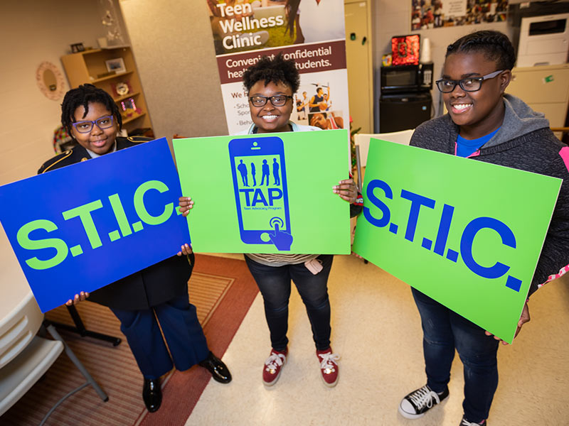 Lanier High School students, from left, Tatiana Myers-Arterberry, Shakell James and Amiracle Williams hold signs touting the school's Teen Advocacy Program.