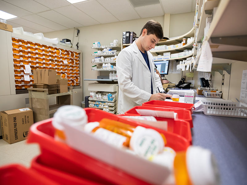 The School of Population Health is teaming with Dispensary of Hope to study the effectiveness of their medication distribution program on health outcomes and costs. UMMC is also in talks with Dispensary about how to bring the program to one of the Medical Center's facilities, such as the Jackson Medical Mall pharmacy where fourth-year School of Pharmacy student Nick Westbrook is shown checking his notes.