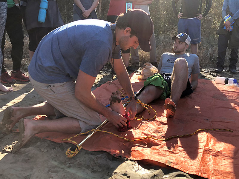 William Salaun, left, ministers to an "injured" Daniel Glover by applying a splint that normally functions as a canoe paddle.