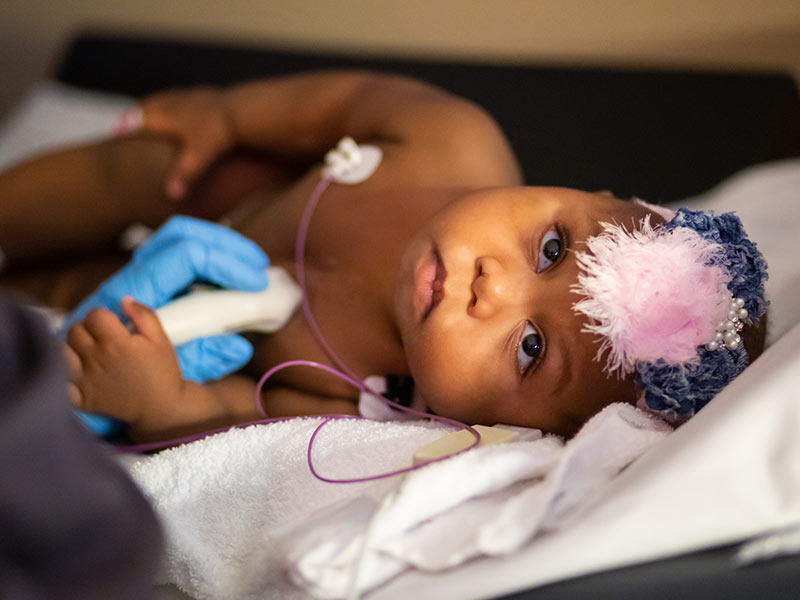Gabrielle "Gabbi" Smith, UMMC's youngest heart transplant patient, holds her sonographer's hand.